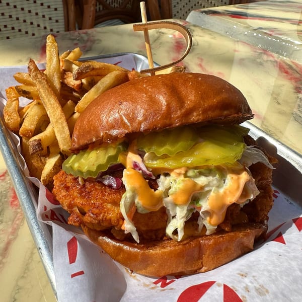 Zalim Hot Chicken & Burgers' fried chicken sandwich with pickles, slaw, and sauce, served with fries.