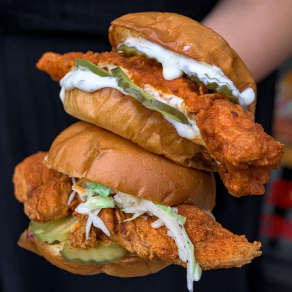 Two stacked Zalim Hot Chicken & Burgers sandwiches with pickles, sauce, and coleslaw.